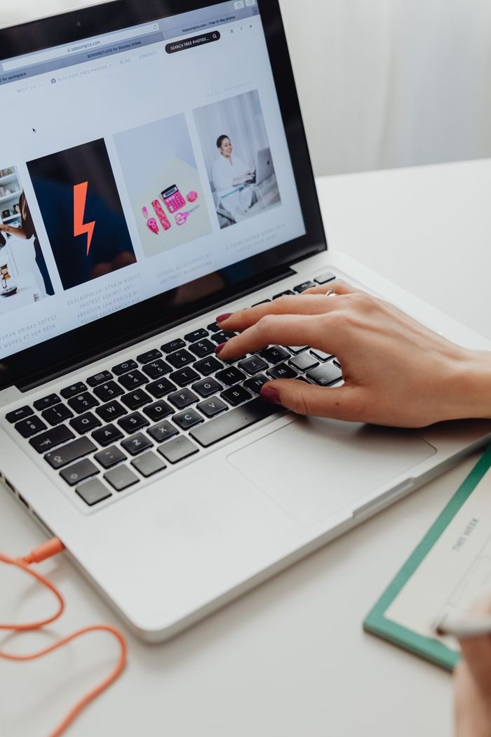 Crafting Captivating Headlines: Your awesome post title goes here Close-up of hand with manicured nails browsing online store on laptop.